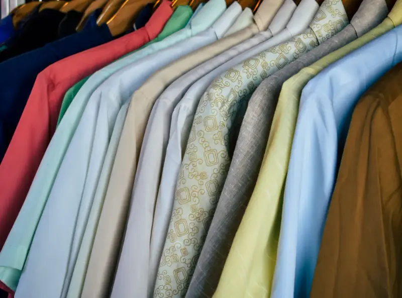 Close row of colorful polo shirts hanging on wooden hangers