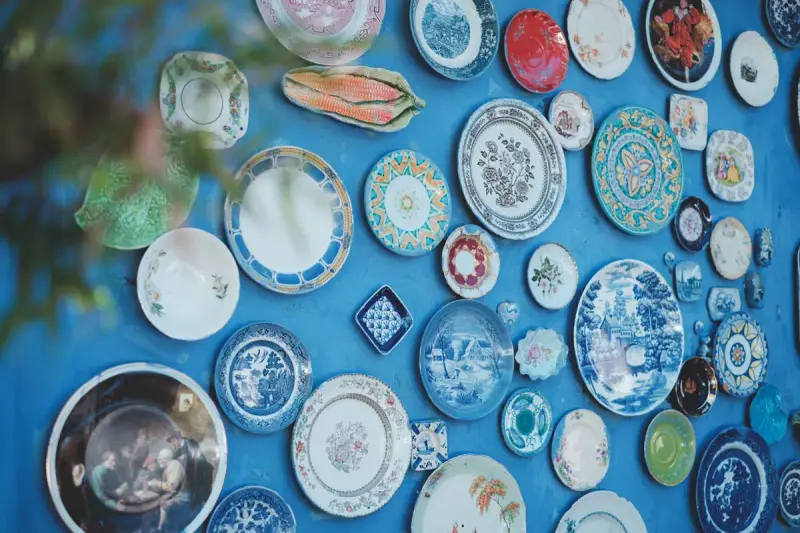 Colorful vintage decorative plates hung across a bright blue wall