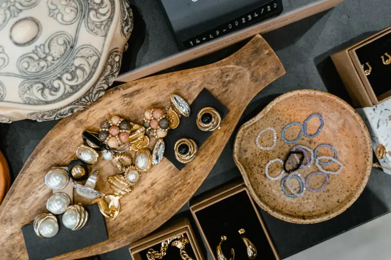 Top view of rings and bracelets in a wooden tray beside a ceramic dish