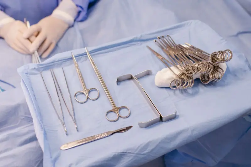 Scissors, clamps, retractors and a scalpel laid out on a blue sterile drape