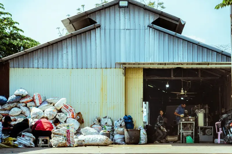 Bags of collected recyclables piled outside the open door of a metal warehouse