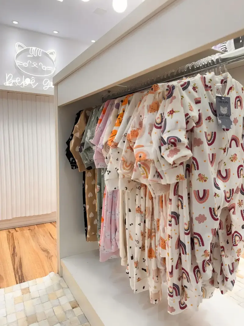 Rack of baby clothes printed with rainbows and clouds in a store