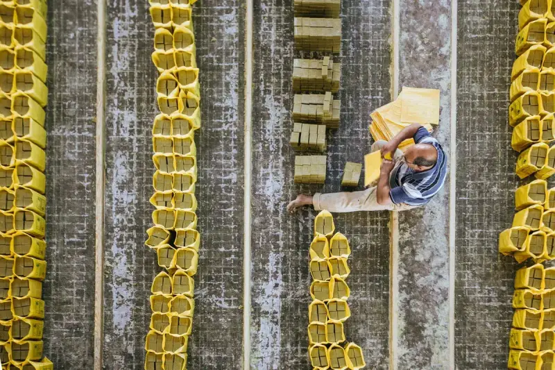 Overhead view of a worker arranging yellow packs of hard soap in rows