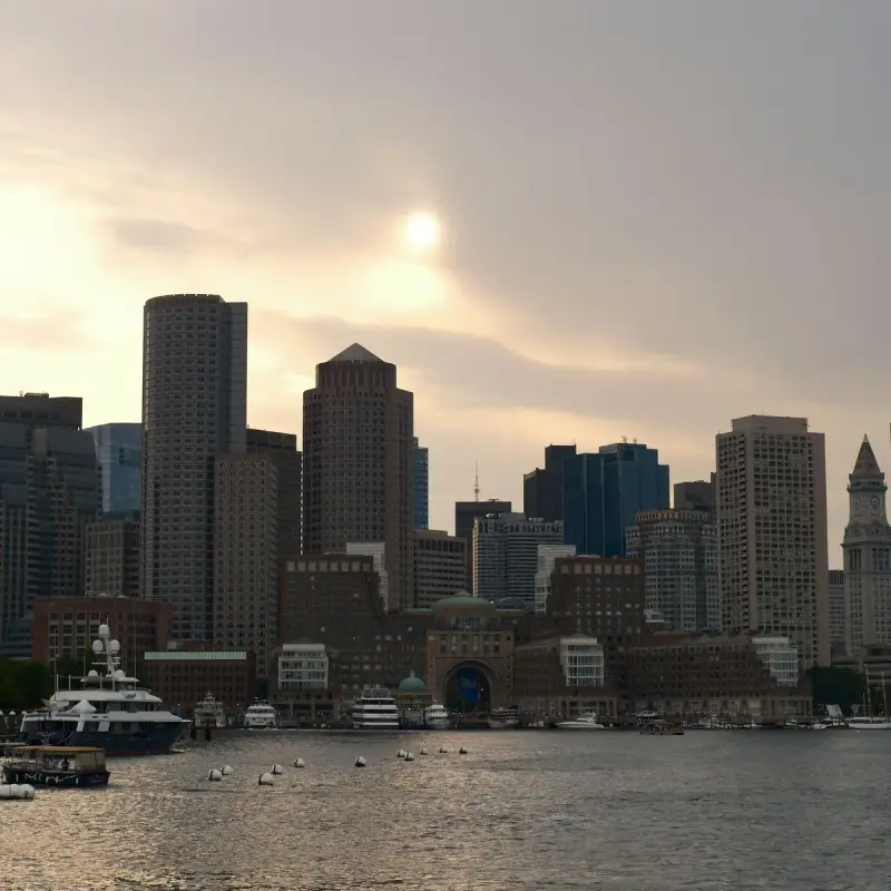 Boston skyline and harbor at dusk with boats along the waterfront