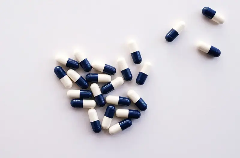 Blue and white capsules scattered on a white surface