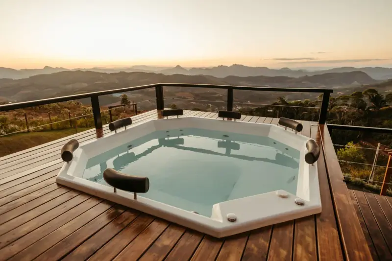 Built-in hot tub set into a wooden deck overlooking mountains at sunset
