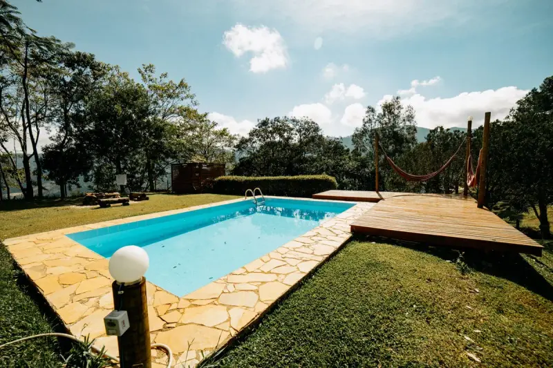 Outdoor pool with flagstone surround and wooden deck on a lawn under a blue sky