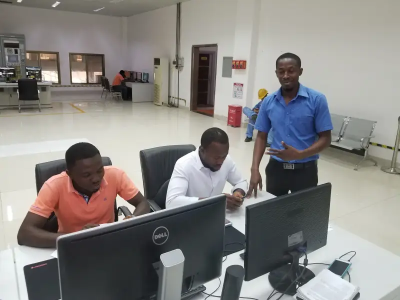 Power plant operators at work beside equipment inside a generating station