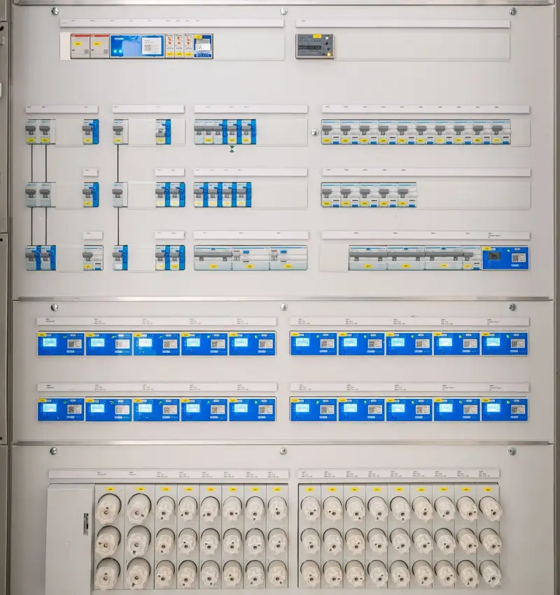 Open distribution panel with rows of circuit breakers and sockets