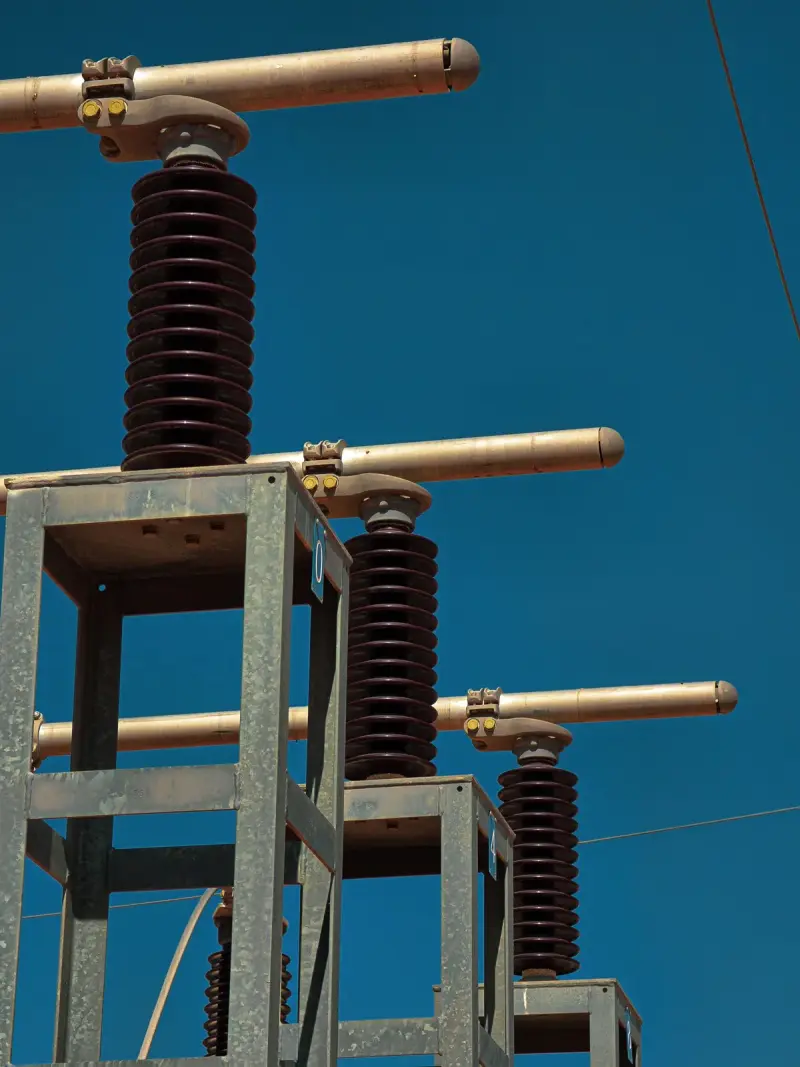 Power transformer bushings and radiators against a bright blue sky