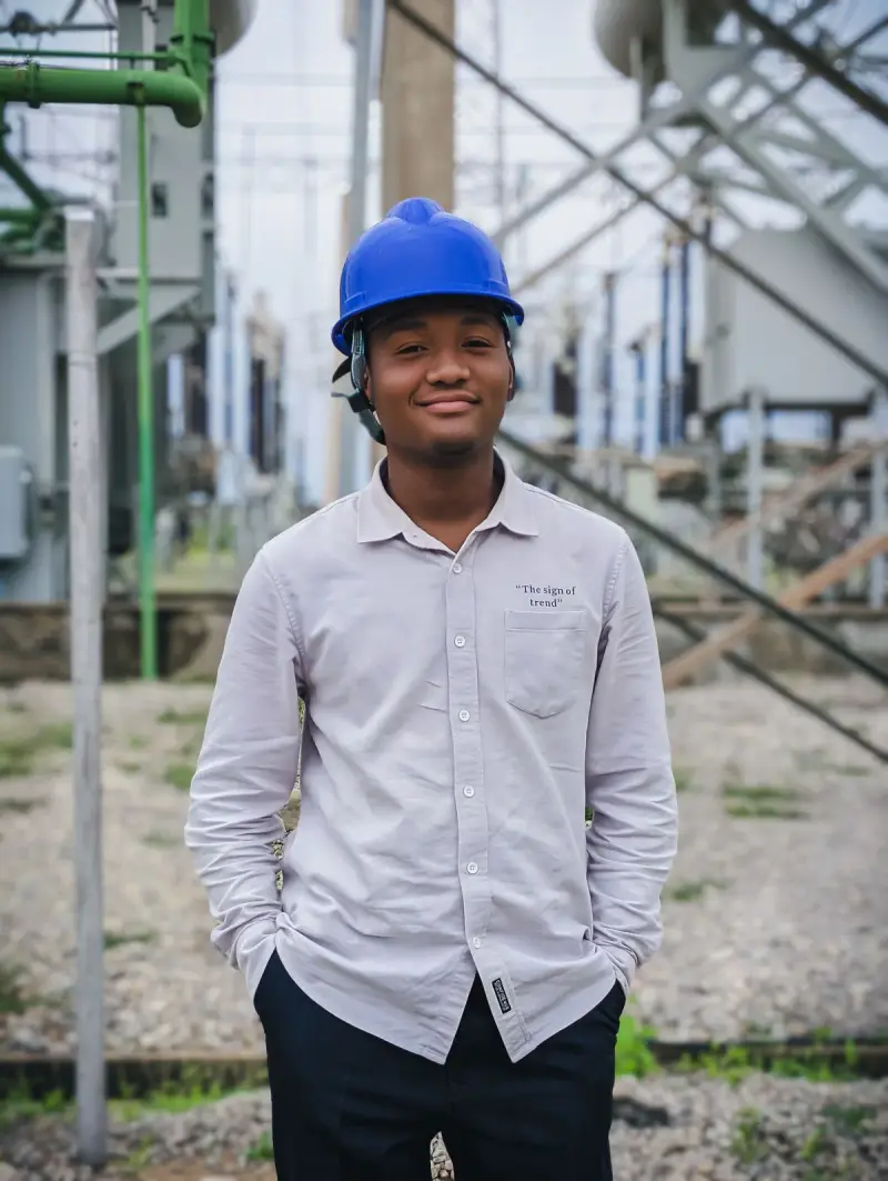 Young engineer in a white hard hat standing inside an electrical substation