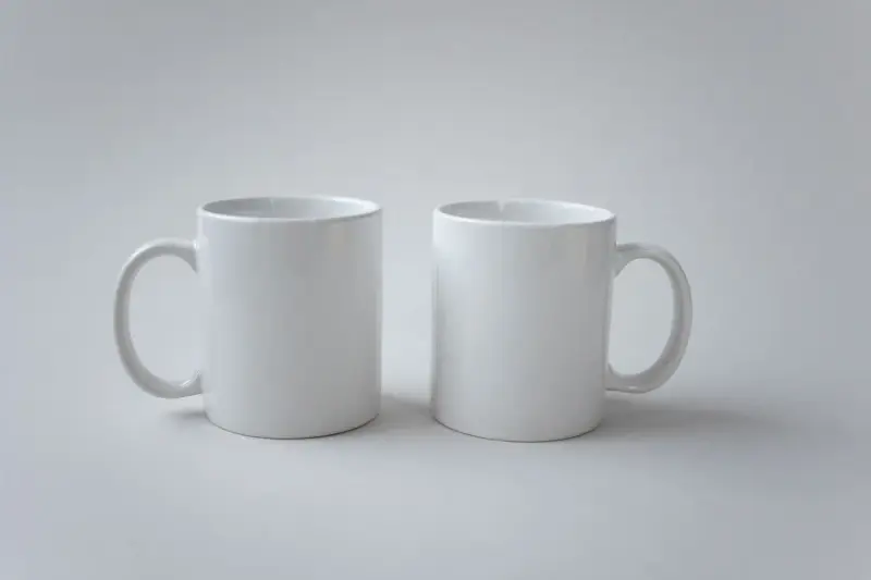 Two plain white ceramic mugs side by side, ready for a printed logo