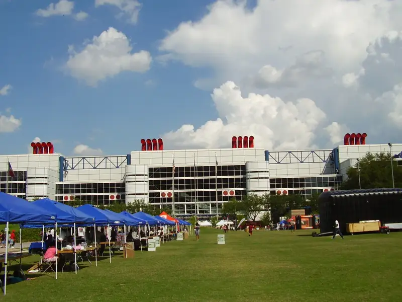 Front of the George R. Brown Convention Center in Houston with its red stacks, seen across the Discovery Green lawn