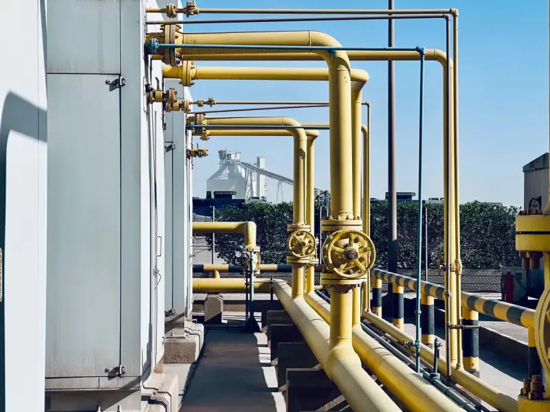 Yellow pipelines and a handwheel valve running along an industrial plant