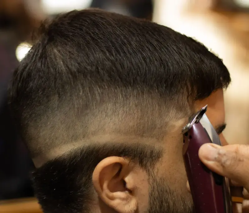Barber using clippers to sharpen a fade haircut, close-up