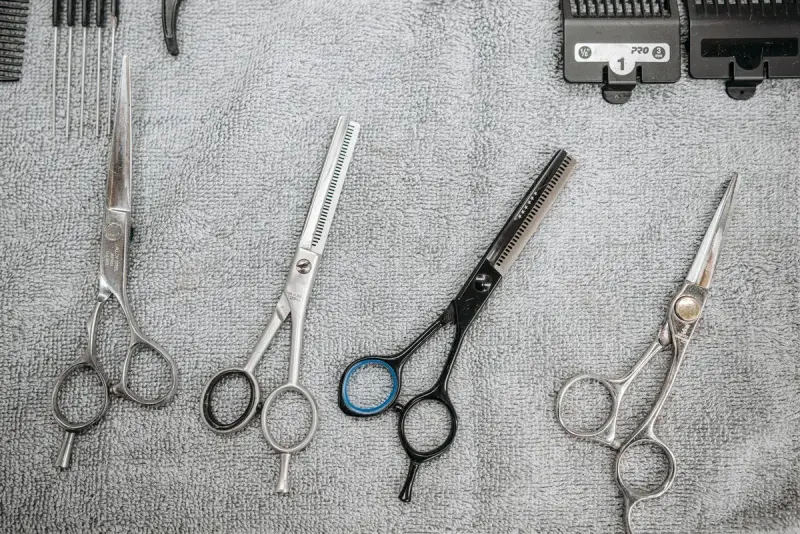 Professional haircutting scissors and combs laid out on a grey towel