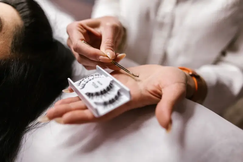 Beautician's hands placing an eyelash extension with fine tweezers