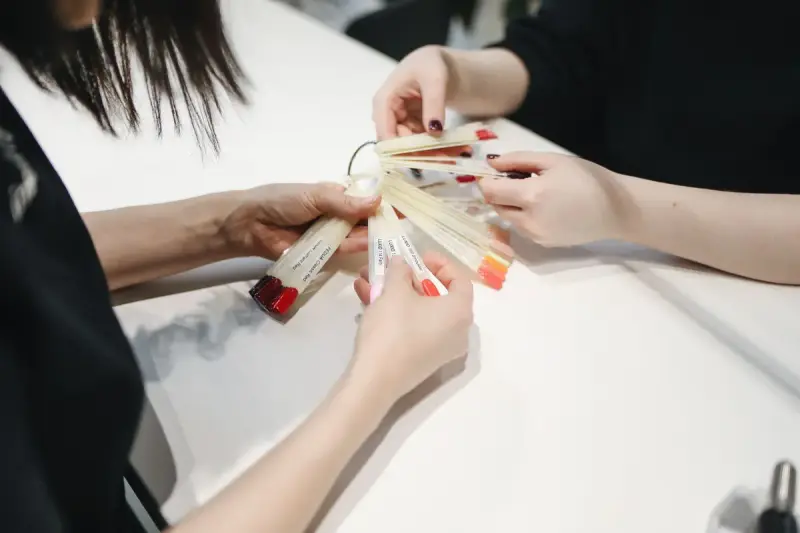 Nail technician fanning out polish swatches for a client to choose a color