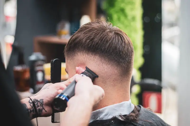Barber trimming a client's hair with clippers in a modern shop
