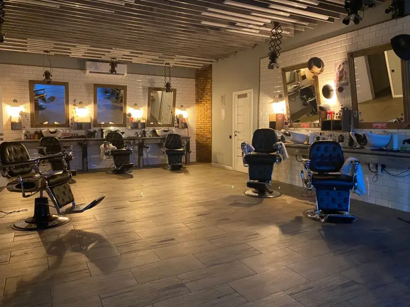 Row of empty salon chairs and mirrors under warm lighting