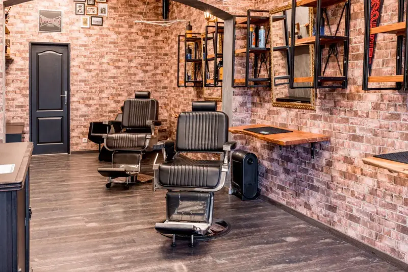 Barber shop with black leather chairs against a rustic brick wall