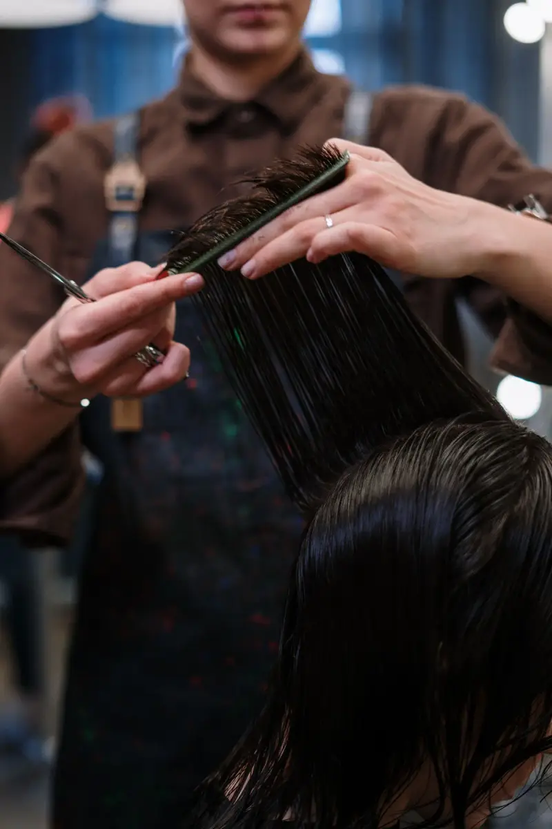 Close-up of a stylist sectioning and cutting wet dark hair