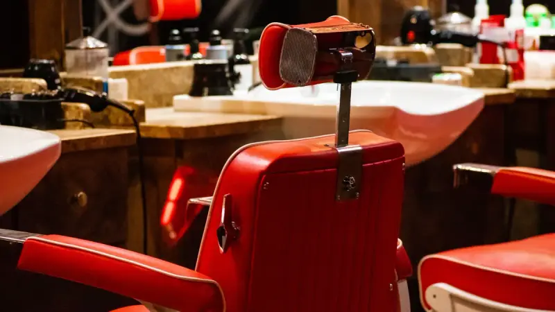 Red barber chair in an empty modern hair salon with mirrors and equipment
