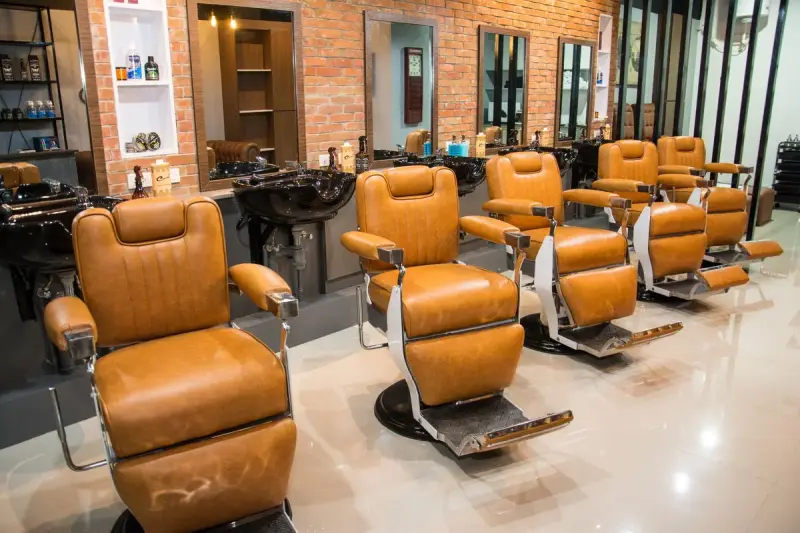 Row of brown leather barber chairs and mirrors in a barbershop