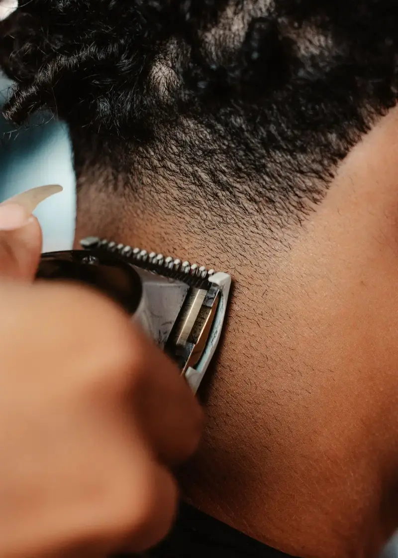 Close-up of clippers cleaning up the neckline of a fade