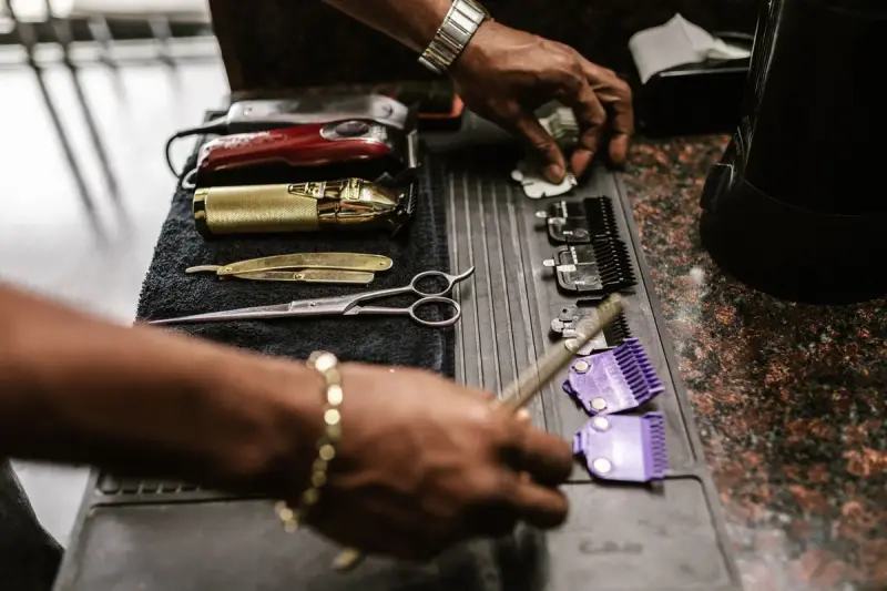 Barber scissors, clippers and combs arranged on a black work mat
