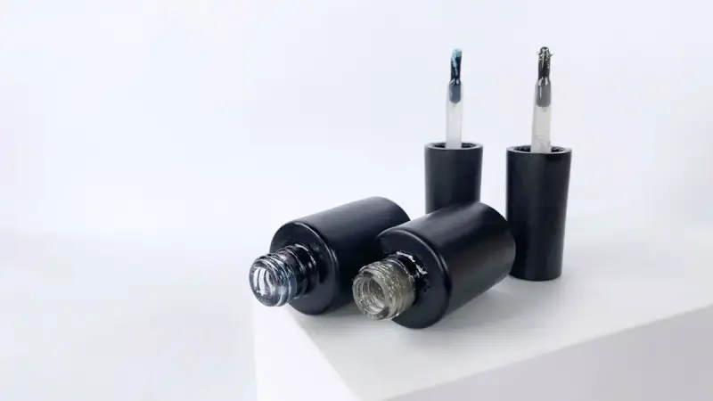 Black nail gel bottles with brushes on a white surface