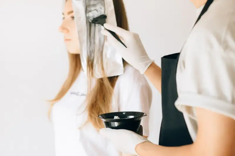 Hairdresser brushing color onto hair sections over foil in a salon