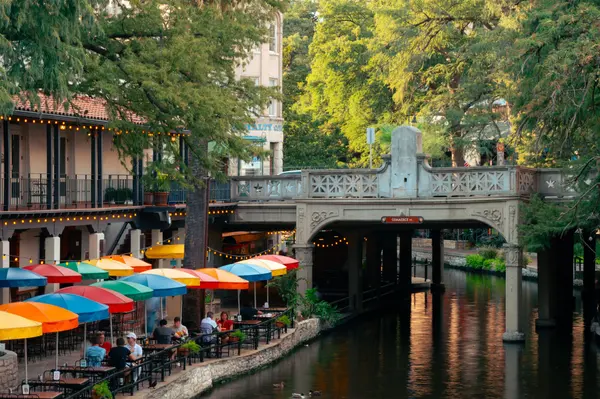 Outdoor dining along the San Antonio River Walk with greenery and a stone bridge