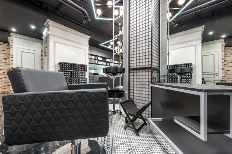 Black leather barber chair facing a large mirror in a modern shop