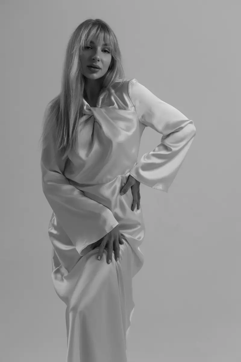 Model in a long-sleeved satin gown posing in black and white