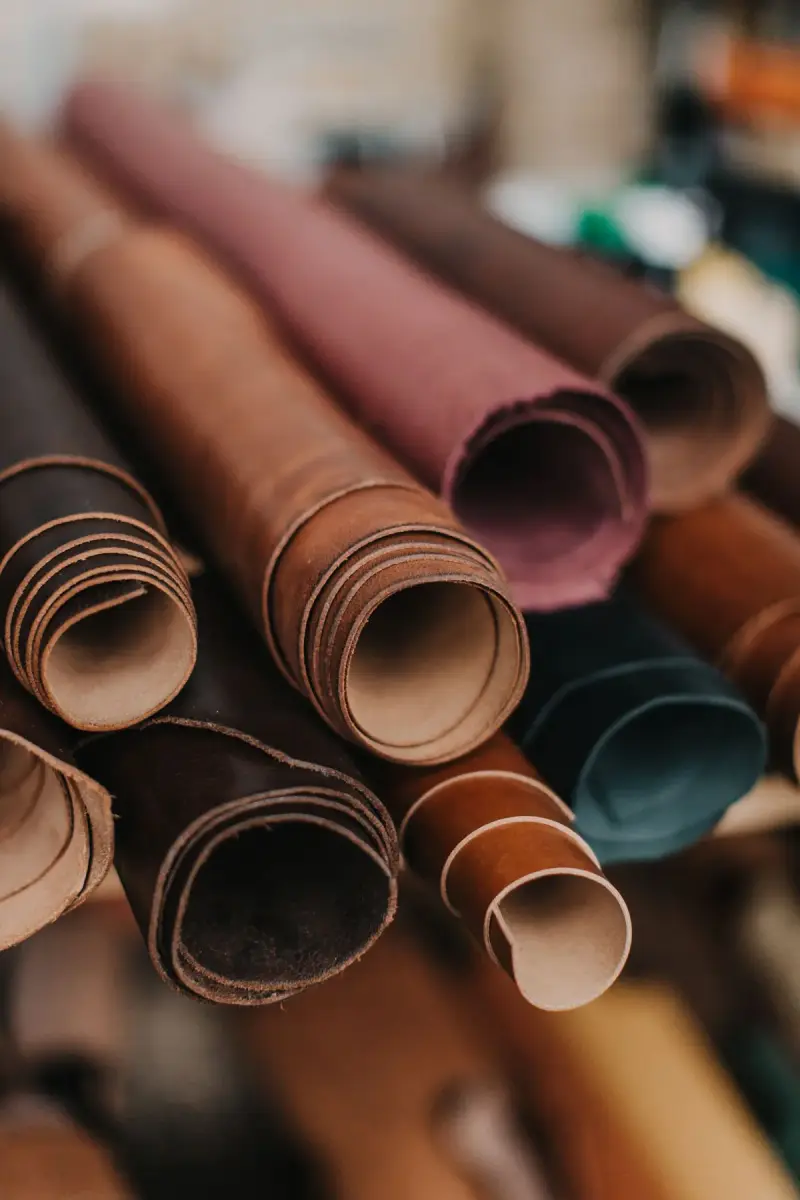 Rolls of brown, burgundy and teal leather hides stacked together