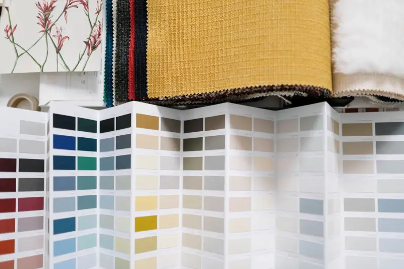 Fabric swatches beside a fan of color chips on a table