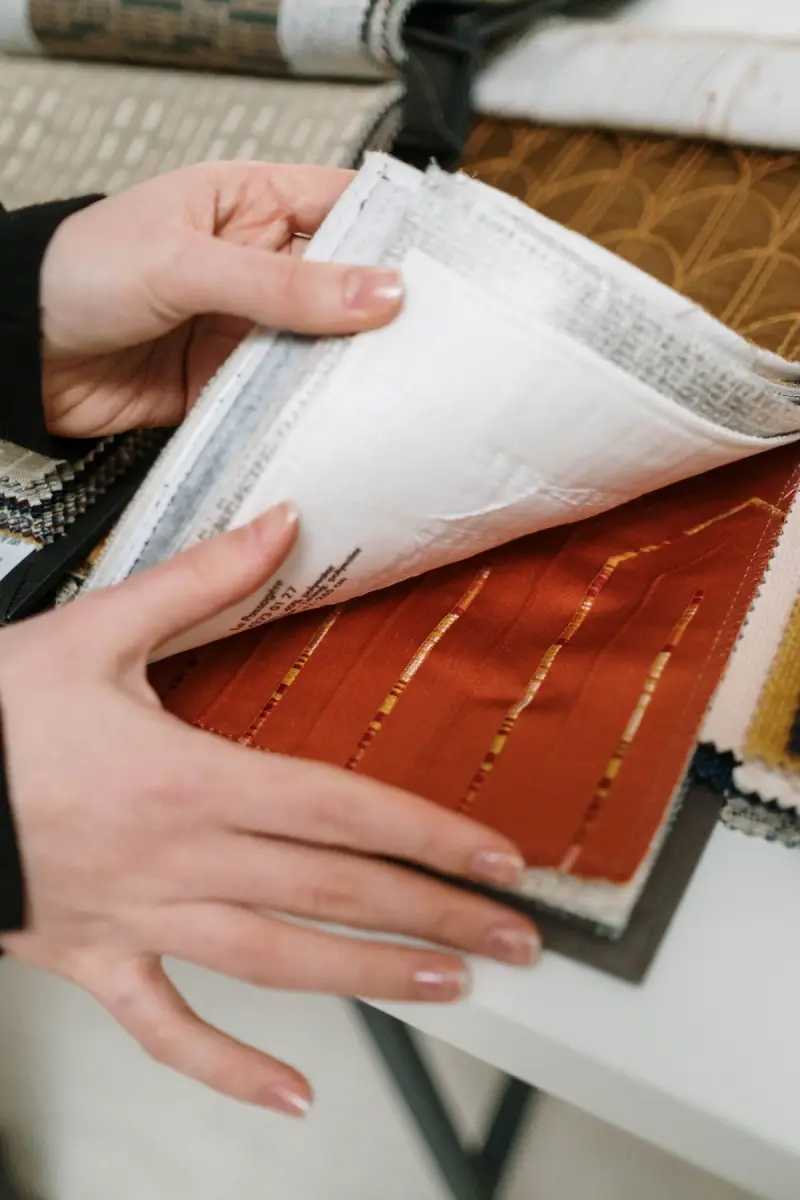 Hand turning the pages of a fabric swatch book with textured samples