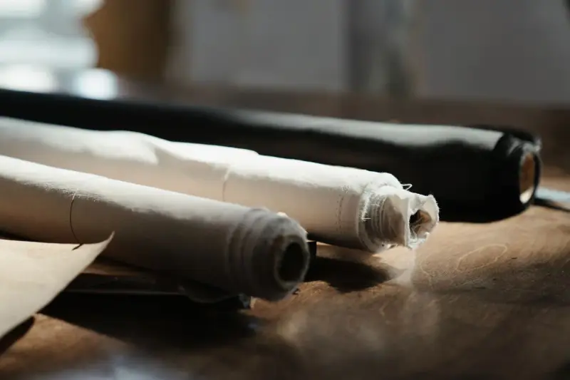 Rolls of fabric lying on a wooden table in an artisan workshop