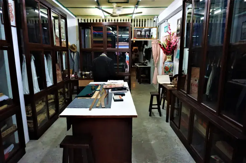 Recreated tailor's workroom with cutting table and garments at a Singapore heritage museum