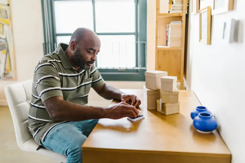 Small business owner preparing packages at a wooden table in a home office