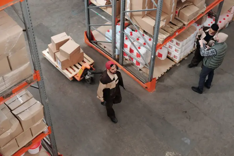 High angle view of workers organizing boxes and pallets between warehouse racks