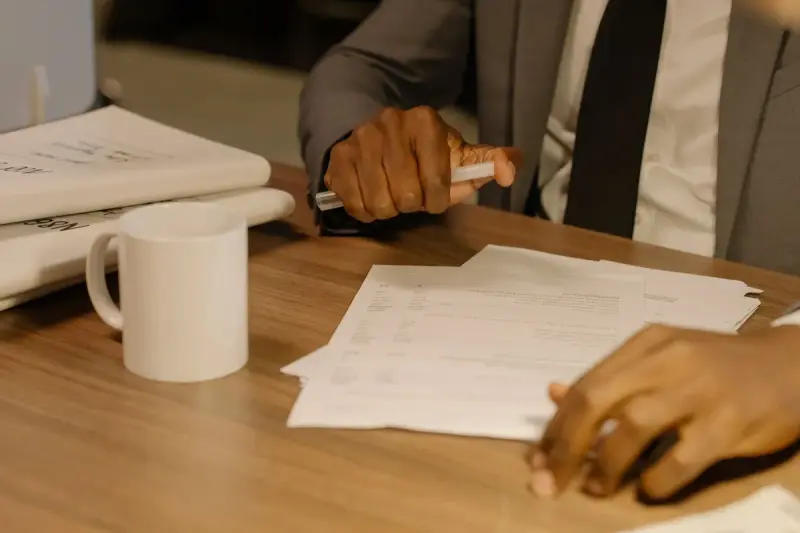 Close-up of hands holding and reviewing printed documents on a wooden desk