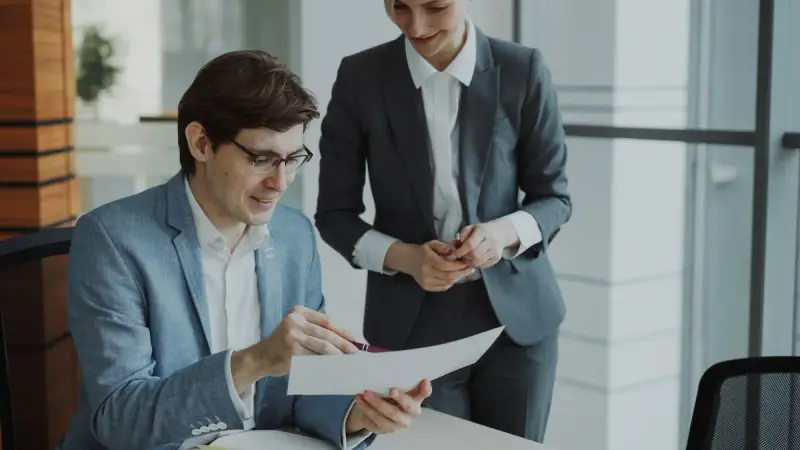 Two business professionals discussing a document in a modern office