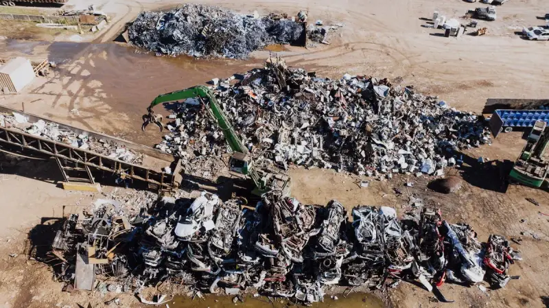 Aerial view of a scrap metal yard with sorted piles and a material handler