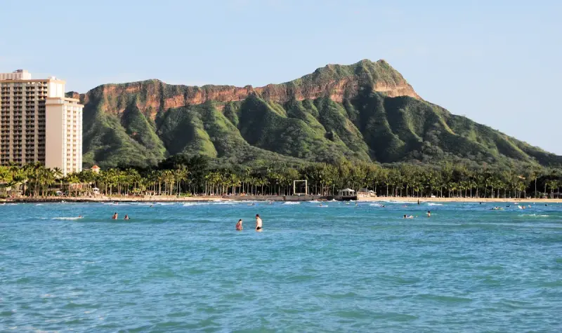 Swimmers in turquoise water off Waikiki Beach with Diamond Head crater behind