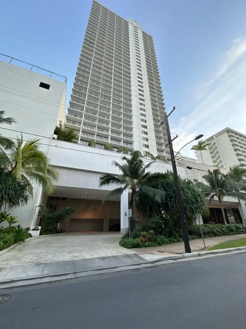 The 'Alohilani Resort Waikiki Beach tower rising above palm trees on Kalakaua Avenue in Honolulu