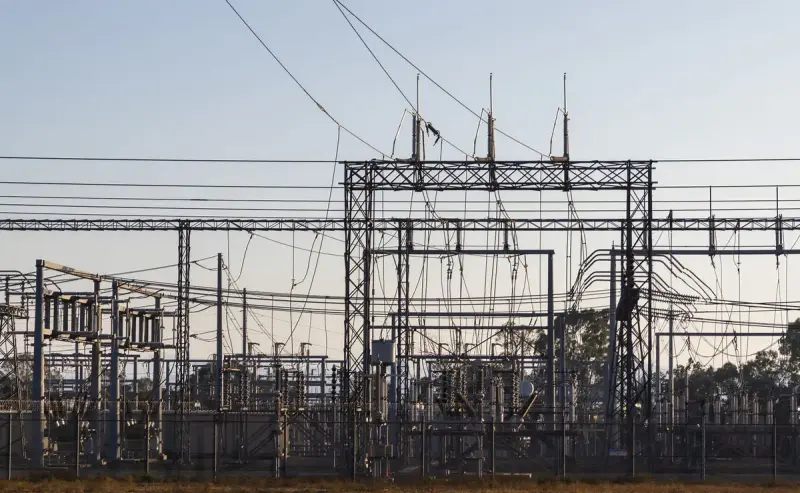 High-voltage electrical substation with steel structures and power lines at dawn