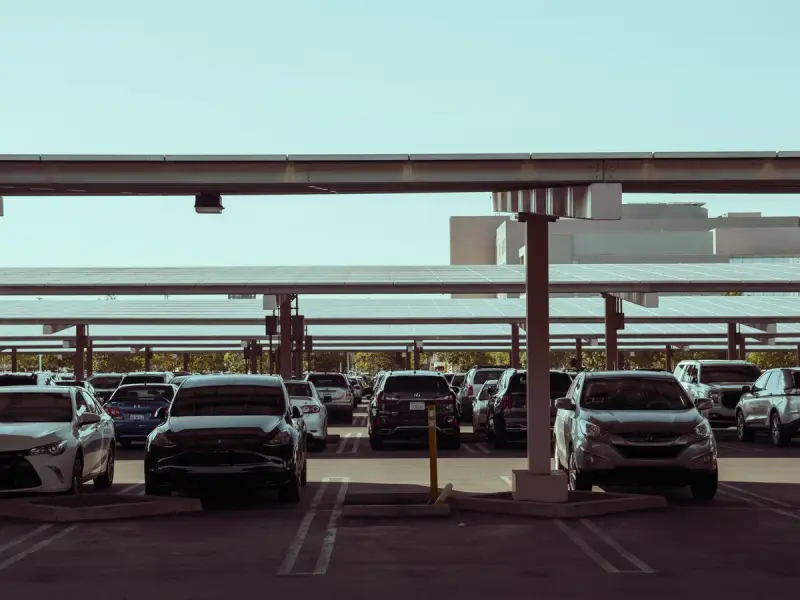 Cars parked under solar panel canopies in a modern lot