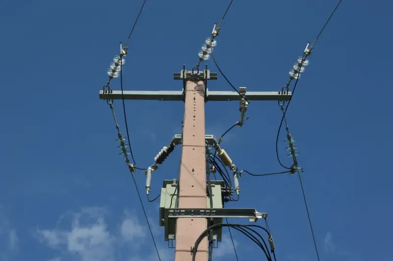 Low angle view of a utility pole and power lines against a blue sky